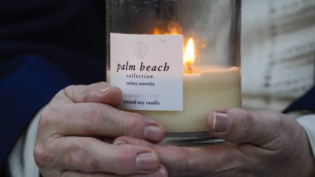 Eine Person hält eine Kerze während einer Mahnwache in Erinnerung an die Opfer der Bluttat in der Bondi Junction Mall in Sydney vor knapp einer Woche. Foto: Mark Baker/AP/dpa