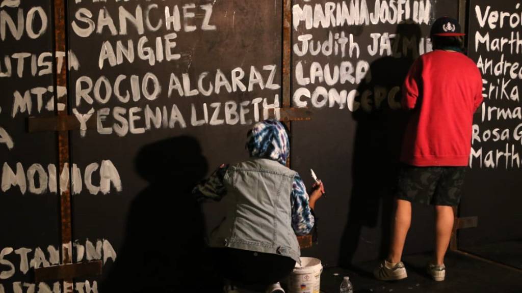 Frauen bemalen die Metallbarrieren des Nationalpalastes mit Namen von Opfern von Femiziden.  Vor geplanten Protesten am Weltfrauentag haben Aktivistinnen einen langen Zaun vor dem Präsidentenpalast in Mexiko-Stadt mit Namen von ermordeten Frauen voll geschrieben. Foto: El Universal/El Universal via ZUMA Wire/dpa