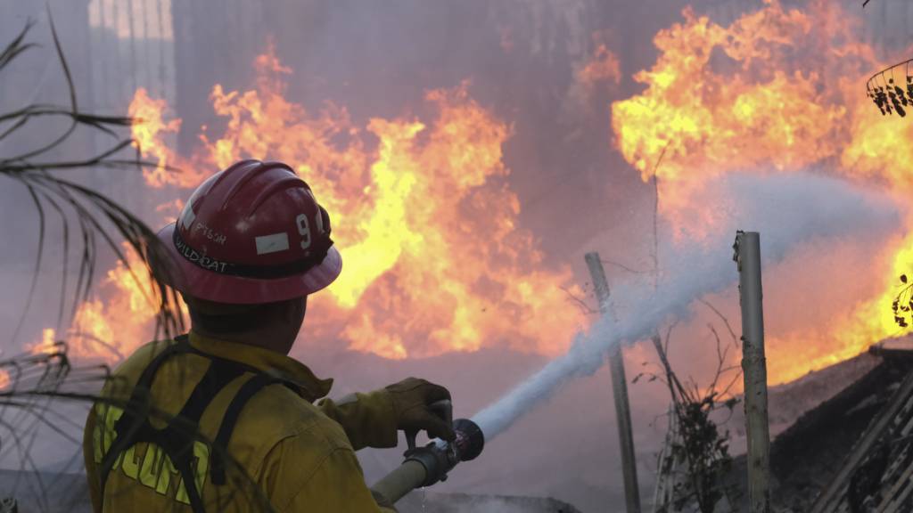 Ein Feuerwehrmann versucht, die Flammen an einem brennenden Haus in Lytle Creek zu löschen, während das «South Fire» brennt. Foto: Ringo H.W. Chiu/AP/dpa