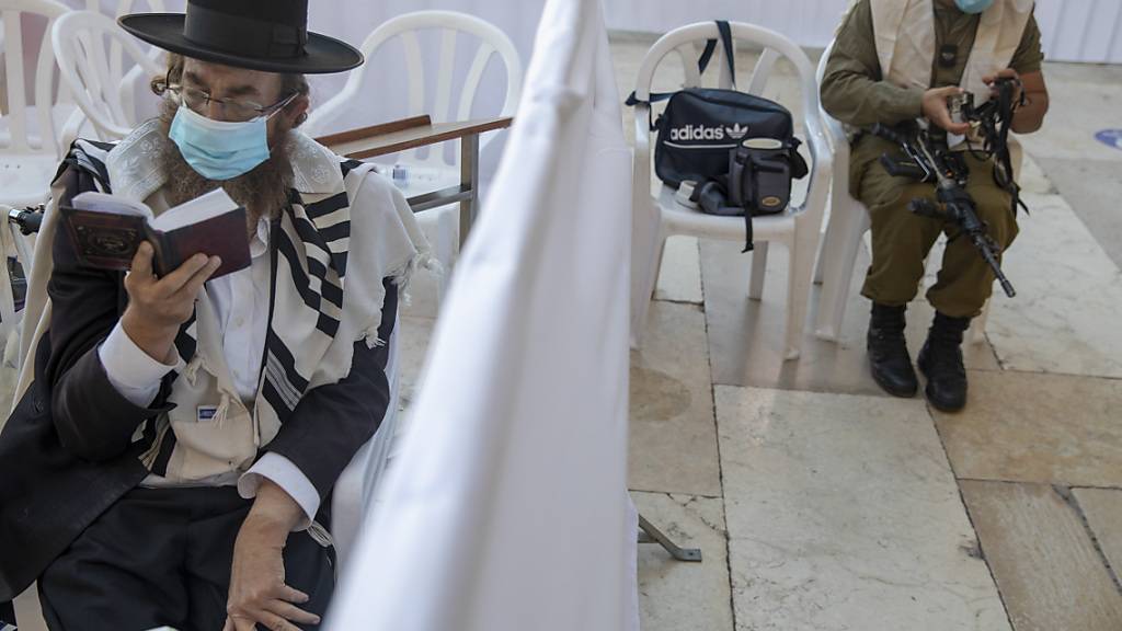 Ein ultra-orthodoxer jüdischer Mann betet in Jerusalem neben einem israelischen Soldaten. Foto: Ariel Schalit/AP/dpa
