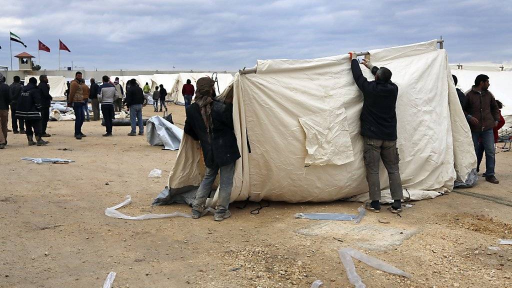 Helfer errichten ein Zelt in einem Flüchtlingslager im türkisch-syrischen Grenzgebiet.