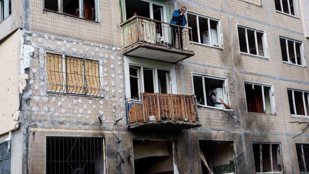 Ein Mann steht auf dem Balkon eines Wohnhauses, das durch einen russischen Drohnenangriff beschädigt wurde. Foto: Evgeniy Maloletka/AP/dpa