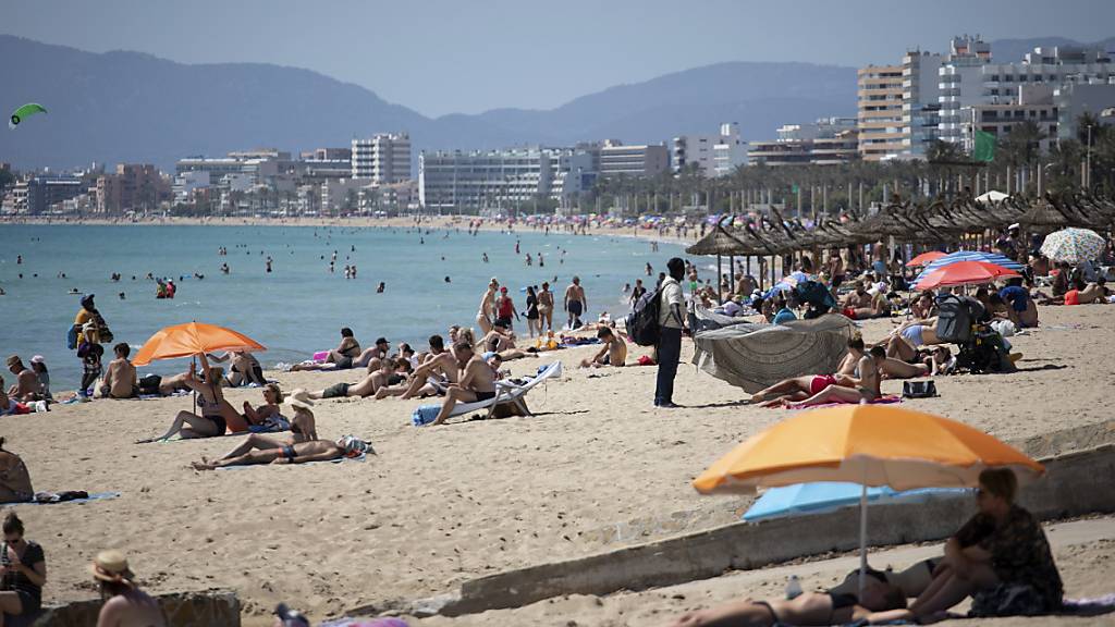 ARCHIV - Touristen genießen die Sonne an einem Strand auf der spanischen Insel Mallorca. Foto: Francisco Ubilla/AP/dpa