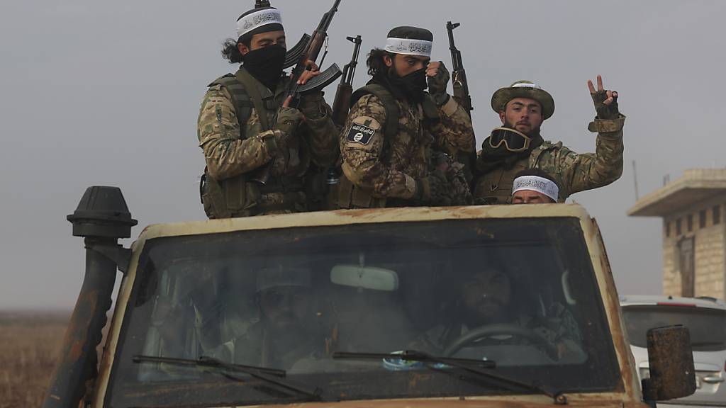Syrische Oppositionskämpfer fahren auf einem Lastwagen durch Talhiya in der Region Idlib, Syrien. Foto: Ghaith Alsayed/AP/dpa