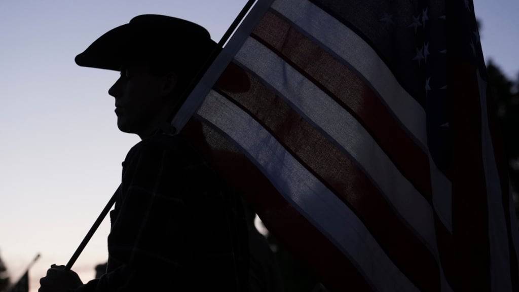 dpatopbilder - Koda hält eine US-Flagge während einer Mahnwache für den rechten US-Aktivisten Charlie Kirk. Foto: Lindsey Wasson/AP/dpa