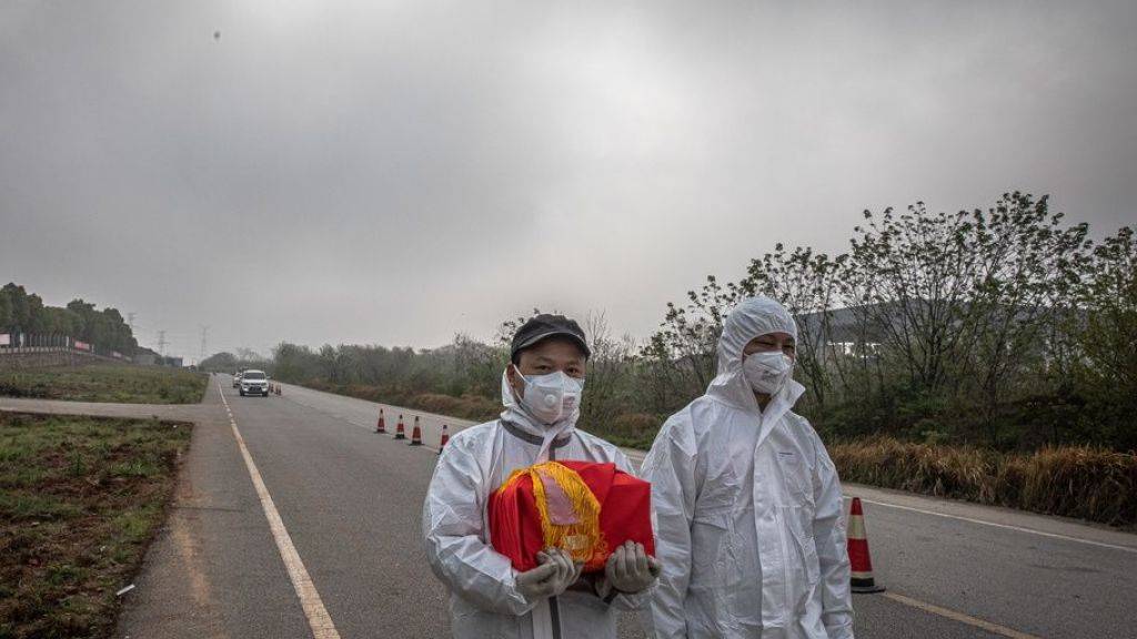 Ein Paar in Wuhan trägt die Asche eines Verwandten nach Hause. Die drastischen Sperrmassnahmen in Wuhan, welches als Epizentrum der Covid-19-Epidemie gilt, hat genützt, wie eine Studie beweist.