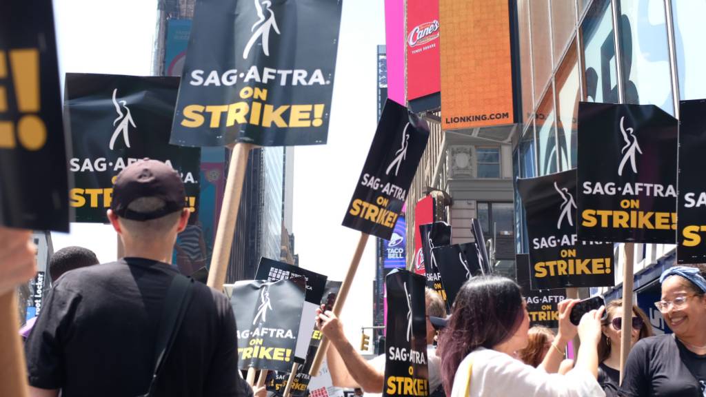 Angehörigen der Gewerkschaft SAG-AFTRA protestieren am Times Square vor dem Rockefeller Center in New York für bessere Vergütung und Regelungen beim Einsatz von Künstlicher Intelligenz. Foto: Laura Höring/dpa