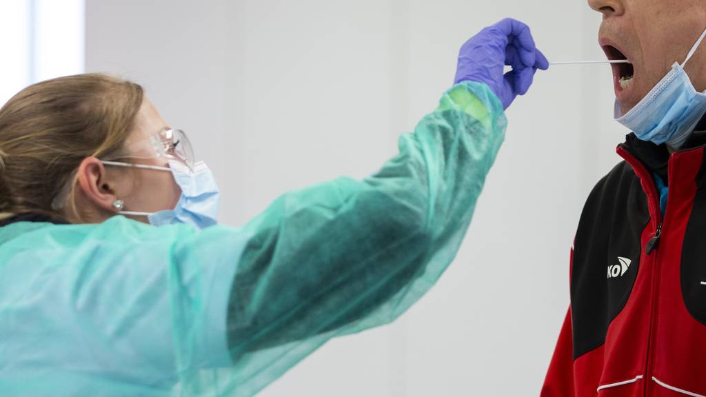 Eine Mitarbeiterin eines mobilen Coronavirus Testcenters in Bern macht einen Abstrich bei einem Mann.