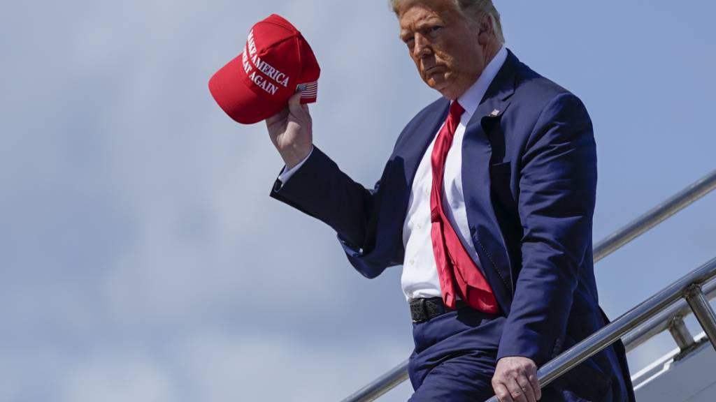 ARCHIV - Donald Trump, damaliger Präsident der USA, steigt am Internationalen Flughafen aus dem Flugzeug und winkt mit der «Make America Great Again»-Kappe. Foto: Evan Vucci/AP/dpa