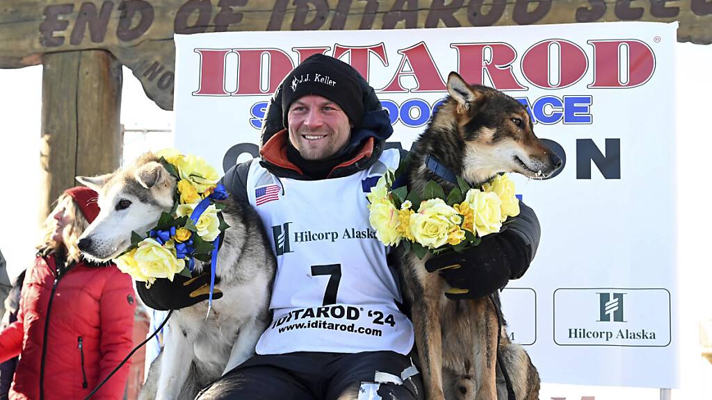 Musher Dallas Seavey zwischen seinen Leithunden Sebastian (l) und Aero nach seinem sechsten Sieg beim 52. Iditarod-Rennen. Foto: Anne Raup/Anchorage Daily News via AP/dpa
