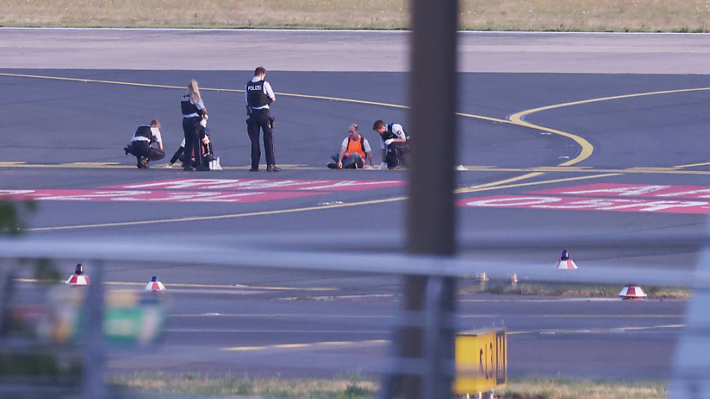 Polizisten versuche im Juli auf dem Flugfeld in Düsseldorf Aktivisten der Gruppe Letzte Generation vom Asphalt zu lösen. (Archivbild)