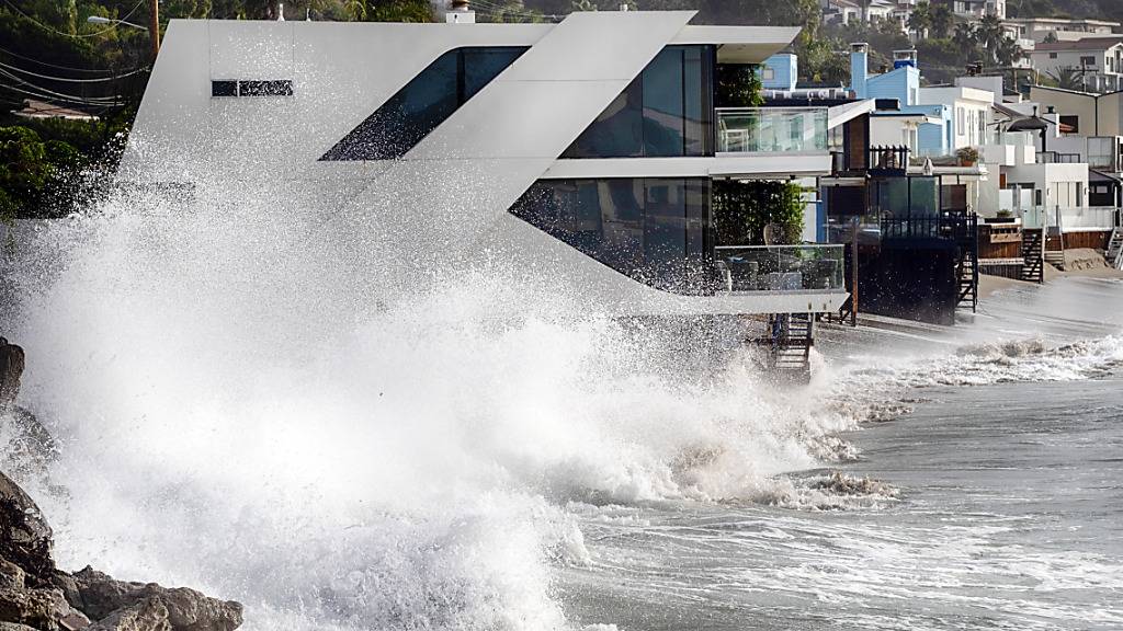 Wellen schlagen gegen ein Haus an der kalifornischen Küste in Malibu Beach.