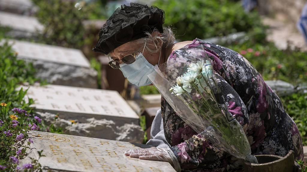 Eine Frau mit Schutzmaske und Handschuhen am Grab ihres Bruders: Israel gedenkt inmitten der Corona-Krise seiner getöteten Soldaten und Terroropfer.