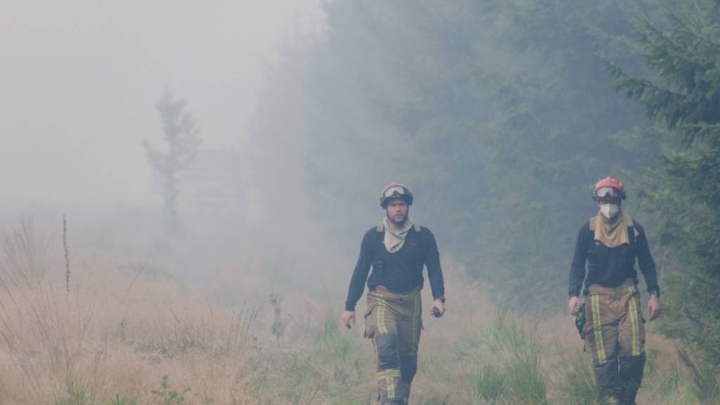 Feuerwehrleute gehen im Waldbrandgebiet. Im Naturschutzgebiet Hohes Venn nahe der deutschen Grenze wütet ein Großbrand. Foto: Nicolas Lambert