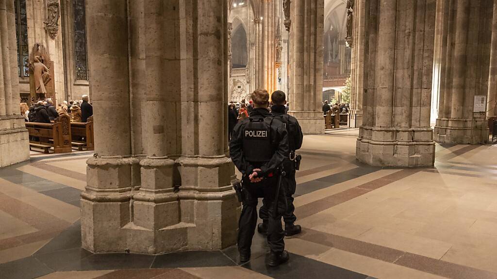 Polizeibeamte sichern während der Silvester-Messe den Kölner Dom. Foto: Thomas Banneyer/dpa