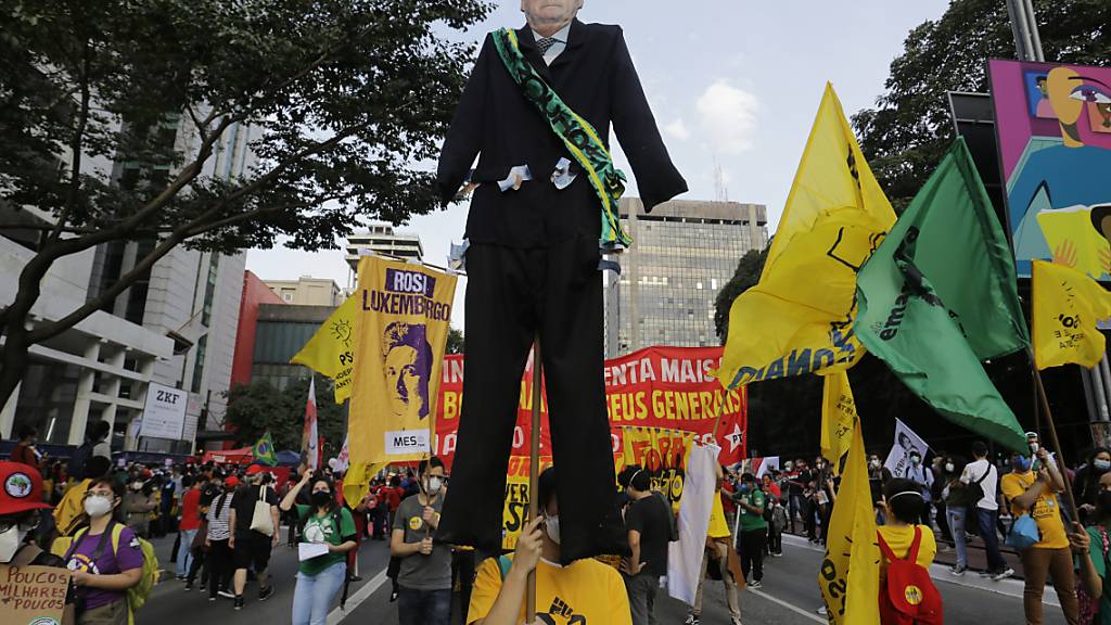Menschen, die an einem Marsch auf der Avenida Paulista teil, um den Rücktritt des brasilianischen Präsidenten Jair Bolsonaro zu fordern, tragen einen riesigen Ausschnitt von Bolsonaro. Foto: Nelson Antoine/AP/dpa