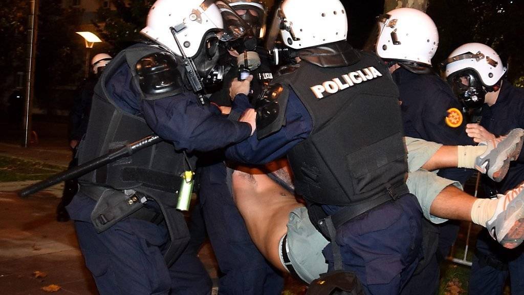 Polizisten tragen einen Mann weg, der bei den Protesten gegen die Regierung in Podgorica verletzt wurde.
