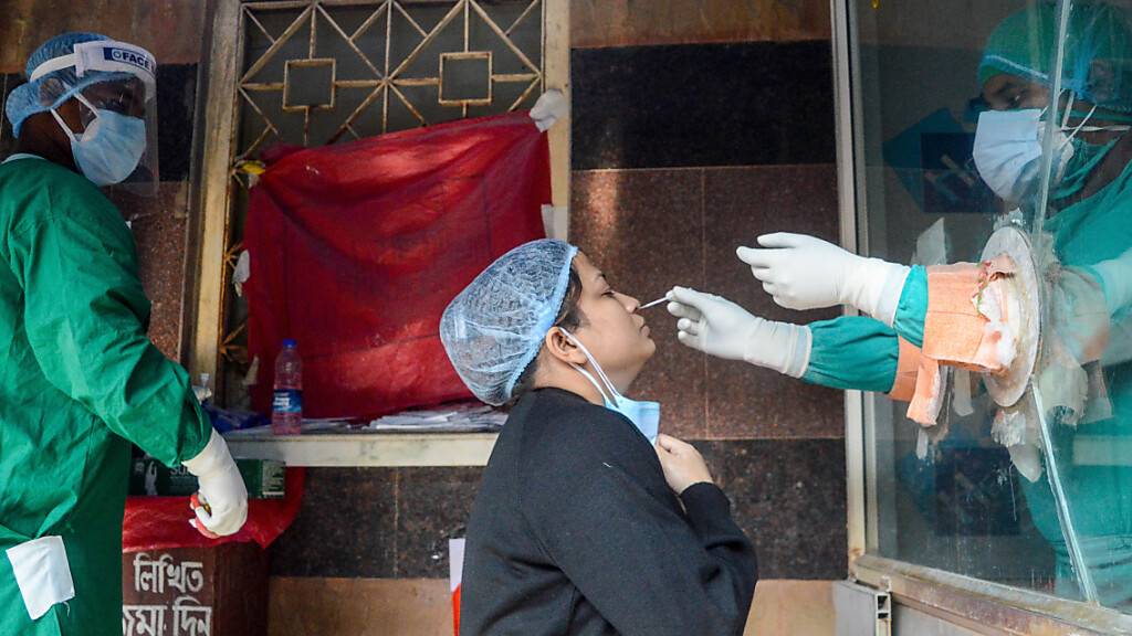 Ein Mitarbeiter des Gesundheitswesens führt einen Nasenabstrich bei einer Frau im indischen Kolkata durch. Foto: Debarchan Chatterjee/ZUMA Press Wire/dpa