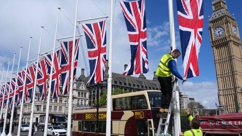 Arbeiter hissen britische Fahnen auf dem Parliament Square. Foto: Kin Cheung/AP/dpa