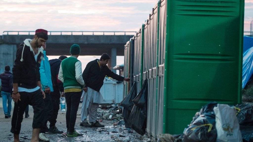 Flüchtlinge im Lager «Neuer Dschungel» bei Calais stehen am Sonntag Schlange vor mobilen Toilettenhäuschen.