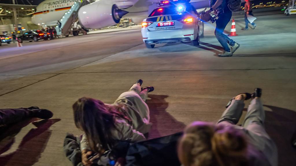 Personen liegen auf dem Flughafen von Tel Aviv vor dem Luftwaffen-Airbus von Bundeskanzler Scholz auf dem Boden. Foto: Michael Kappeler/dpa Pool/dpa