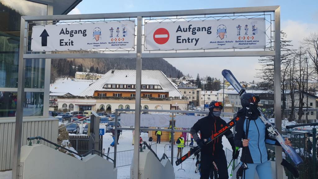 Skifahrer gehen in Semmering unter Schildern, die auf die coronabedingten Hygieneregeln hinweisen, durch.