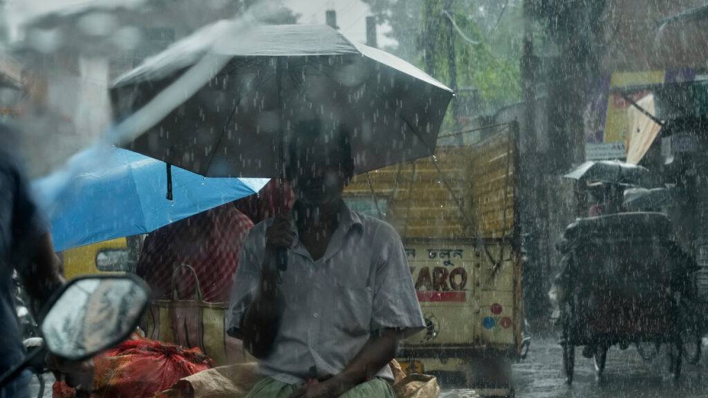dpatopbilder - Pendler sind in einer Rikscha im Mittagsregen in Kalkutta unterwegs. Foto: Bikas Das/AP/dpa