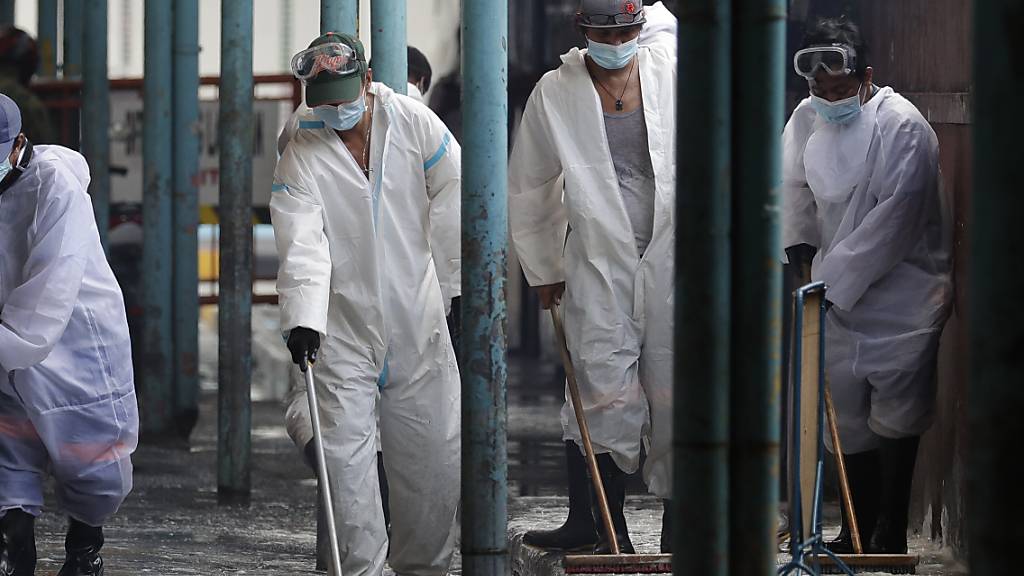 Arbeiter in Schutzanzügen desinfizieren einen Markt als Maßnahme gegen die Verbreitung des Coronavirus. Foto: Aaron Favila/AP/dpa