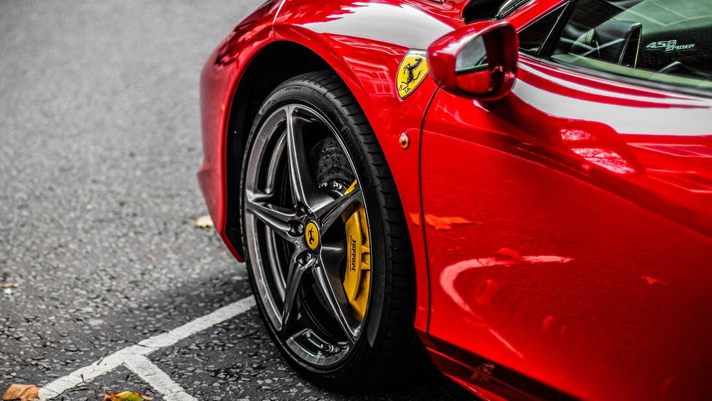 Im Bild: Ein roter Ferrari, der auf einem Parkplatz parkiert. 