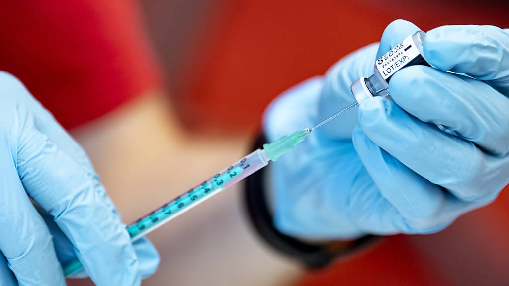 Ein Notfallsanitäter zieht den Corona-Impfstoff von Biontech in eine Spritze.