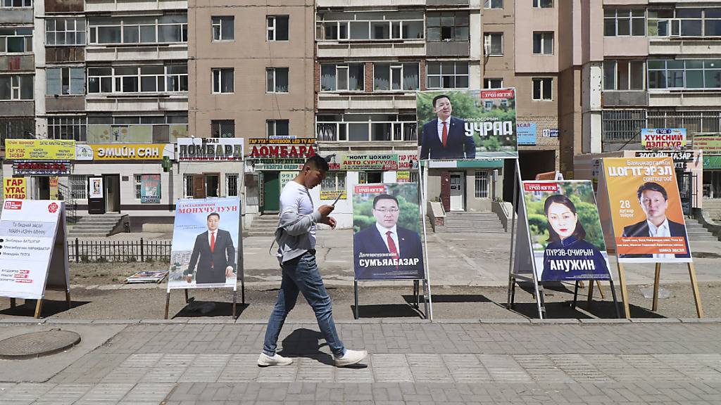 Ein Mann geht an Wahlplakaten verschiedener Parteien vorbei.