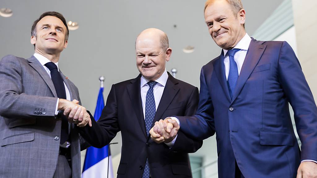 Emmanuel Macron (l-r), Präsident von Frankreich, Bundeskanzler Olaf Scholz und Donald Tusk, Ministerpräsident von Polen, schütteln sich am Ende eines Pressestatements die Hände. Foto: Christoph Soeder/dpa