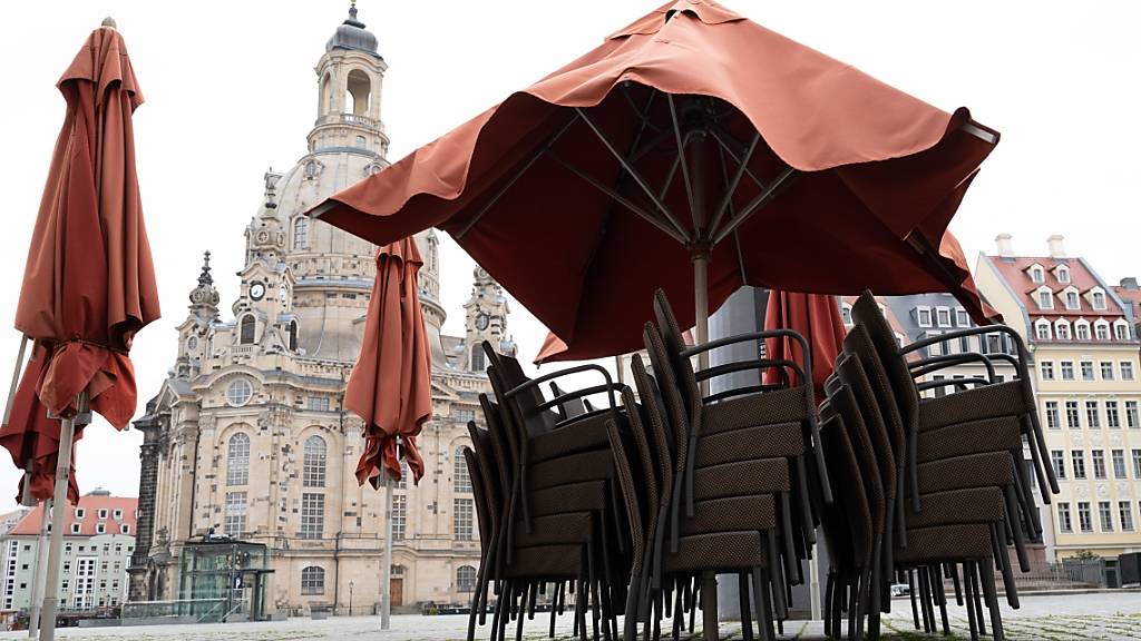 Leere Stühle stapeln sich vor einem Restaurant auf dem Neumarkt vor der Dresdener Frauenkirche. Die Menschen in Deutschland müssen sich ab dem Wochenende auf neue Corona-Beschränkungen einstellen. Foto: Sebastian Kahnert/dpa-Zentralbild/dpa