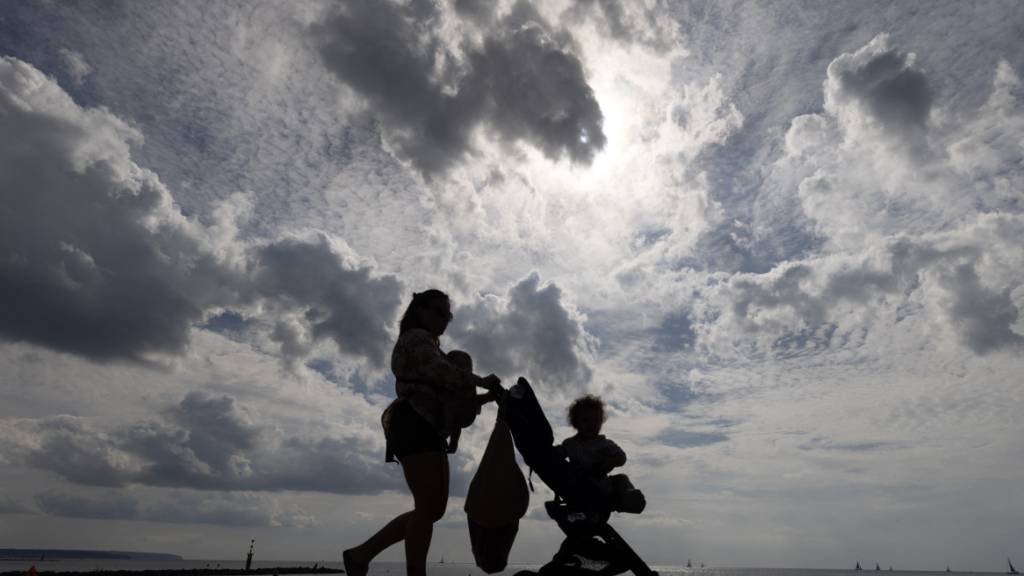 Eine Frau spaziert mit ihrem Kinderwagen am Strand Ciudad JardÌn auf Mallorca entlang. Foto: Clara Margais/dpa/Symbolbild