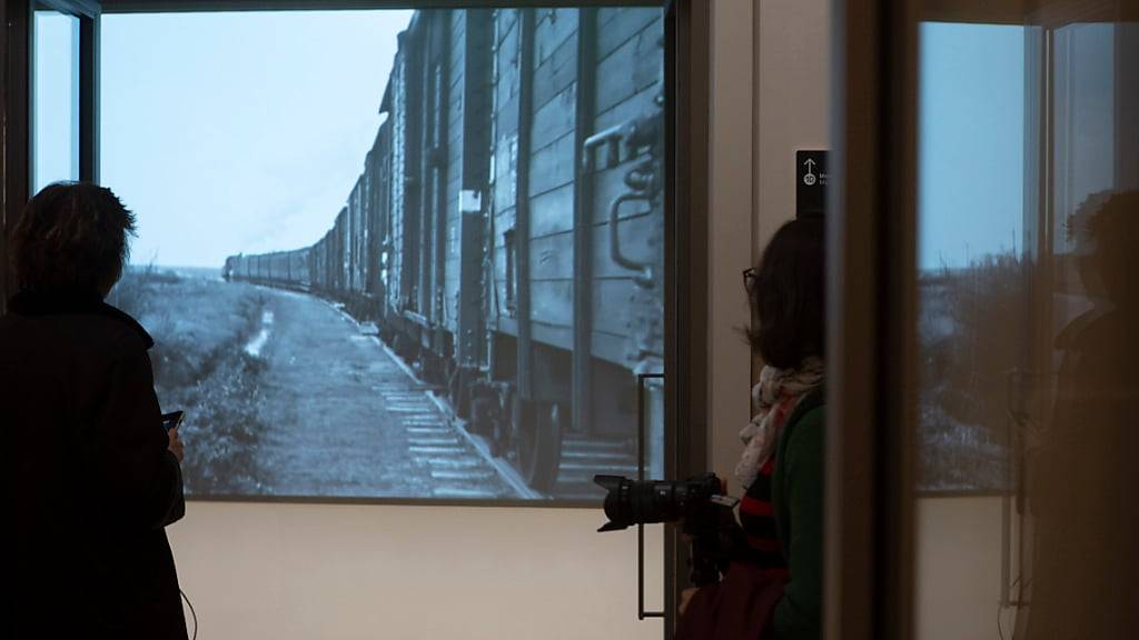 Während einer Pressevorführung des neuen Nationalen Holocaustmuseums sehen sich Menschen historische Aufnahmen von Zügen an, die Juden in Konzentrationslager der Nazis transportieren. Foto: Peter Dejong/AP/dpa