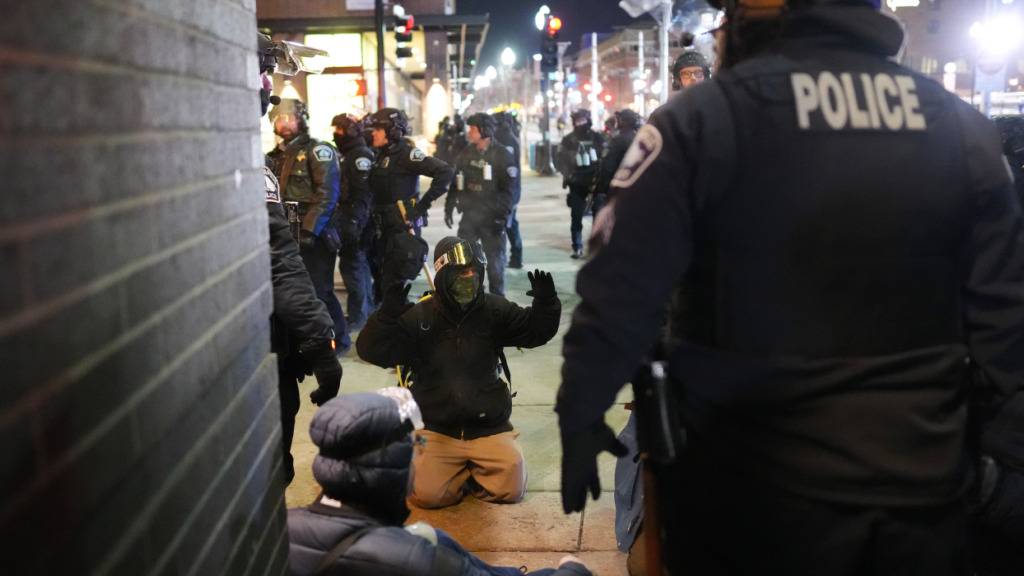dpatopbilder - Ein Demonstrant hebt auf dem Boden die Arme, während Einsatzkräfte nach der Erklärung einer unerlaubten Versammlung bei einer Lärm-Demonstration vor dem Hotel Graduate by Hilton Minneapolis Festnahmen vornehmen. Foto: Adam Gray/FR172090 AP/AP/dpa