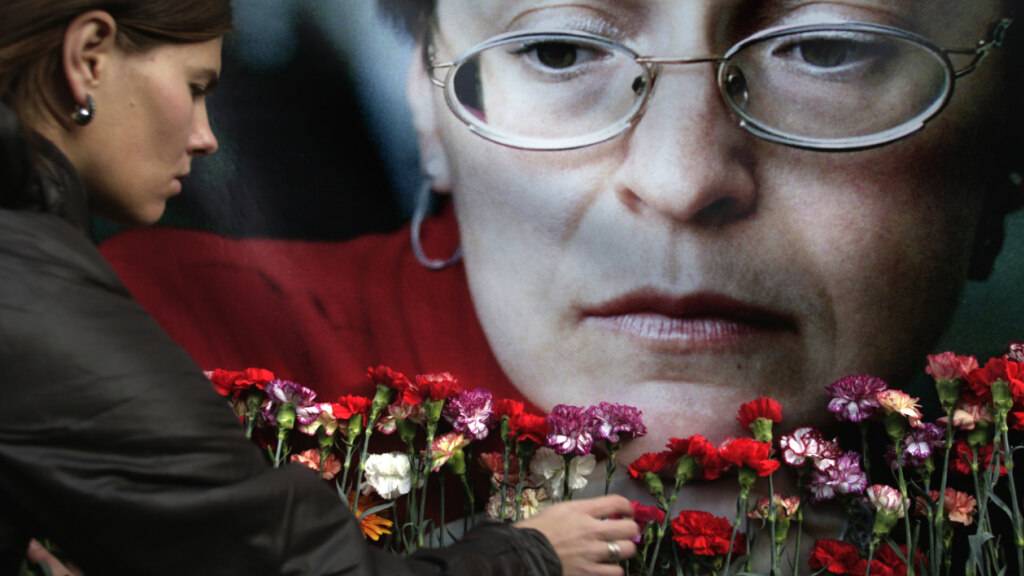 ARCHIV - Eine Frau legt Blumen vor einem Porträt der ermordeten russischen Journalistin Anna Politkowskaja nieder. Foto: Pavel Golovkin/AP/dpa