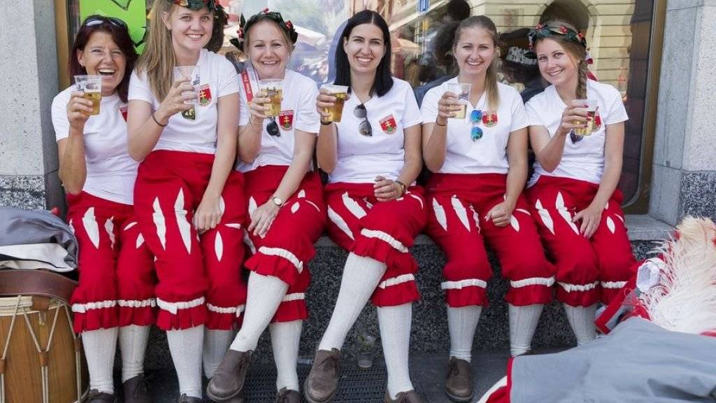 Junge Tambour- und Piccolo-Spielerinnen erfrischen sich am Tambouren- und Pfeiferfest in Bulle bei hochsommerlichen Temperaturen vor dem grossen Abschluss-Umzug.