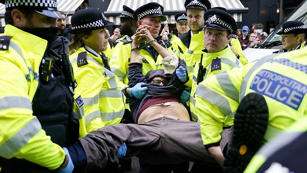Polizisten verhaften einen Demonstranten, der sich während eines von der Umweltschutzbewegung Extinction Rebellion organisierten Protests unter einen Lieferwagen klebte. Bei der Protestaktion in London laut Mitteilung von Scotland Yard am späten Montagabend mehr als 50 Menschen festgenommen worden.
