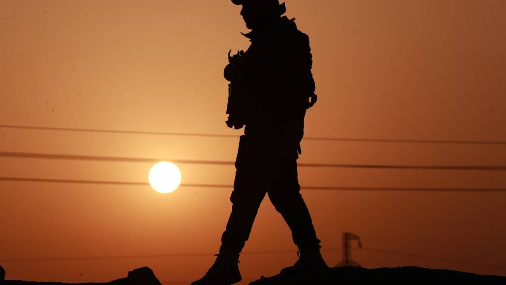ARCHIV - Ein Mitglied der Popular Mobilization Forces an einer Betonmauer an der irakisch-syrischen Grenze in Al-Qaim, im Westen des Irak. Auch im Irak kommt es in mehreren Landesteilen zu Angriffen. Foto: Ameer Al-Mohammedawi/dpa