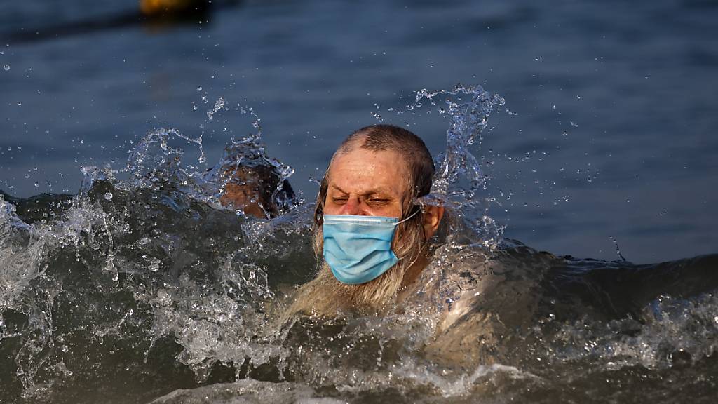 Ein Mann schwimmt mit Mundschutz an einem Strand in Tel Aviv. Foto: Oded Balilty/AP/dpa