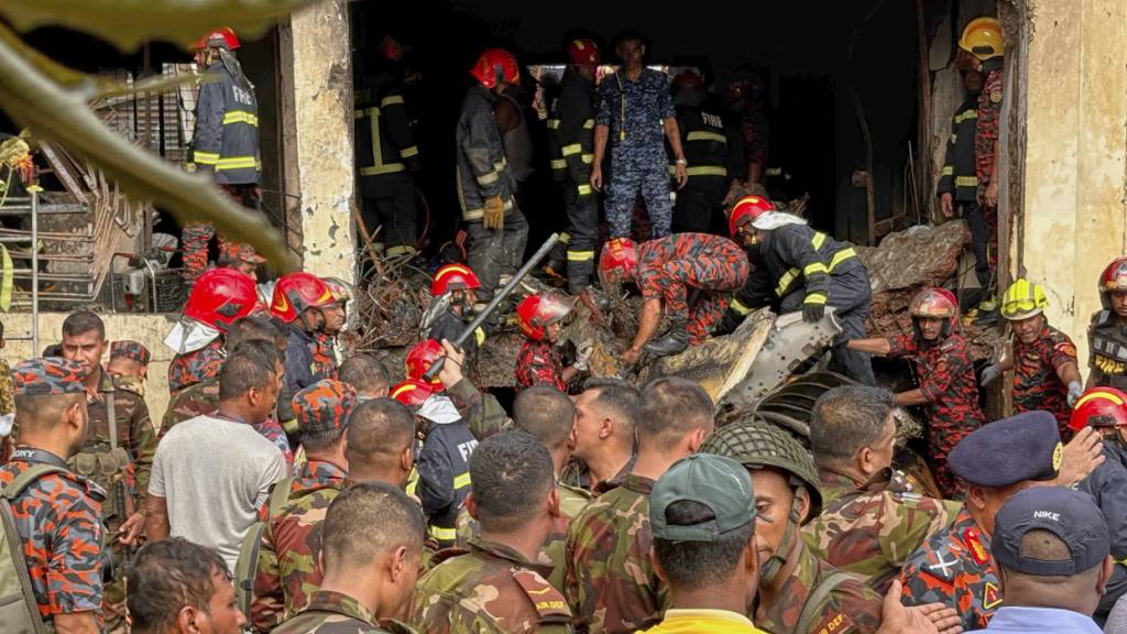 dpatopbilder - Feuerwehrleute untersuchen das Wrack eines Trainingsflugzeugs der Bangladesh Air Force, das auf ein Schulgelände abgestürzt ist. Foto: Al-emrun Garjon/AP/dpa