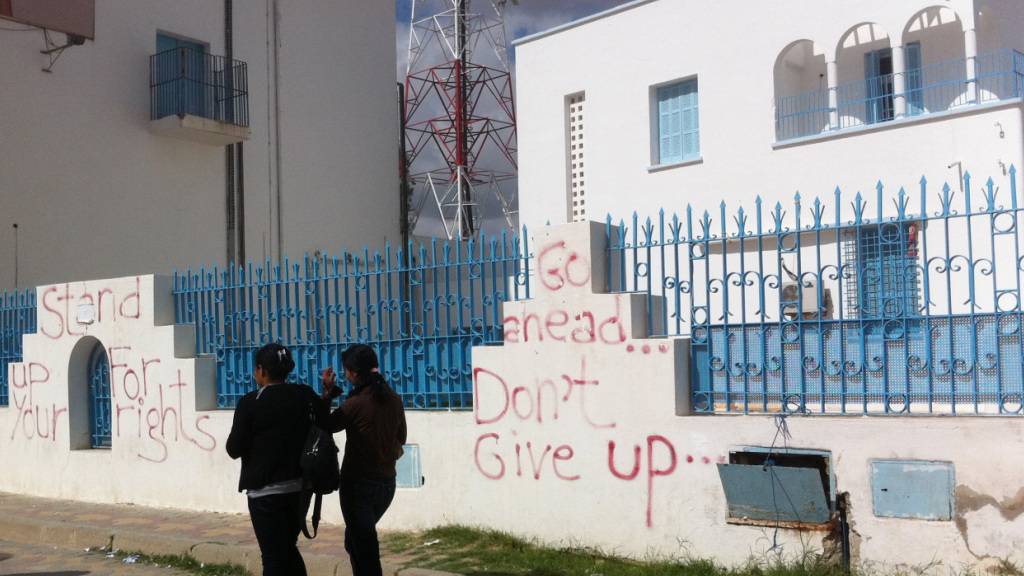 ARCHIV - Passantinnen gehen am 17.10.2011 in Sidi Bouzid an mit Graffiti besprühten Mauern vorbei. (zu dpa «Ein Gemüsehändler zündet sich an: 10 Jahre Aufstände in der arabischen Welt») Foto: picture alliance / dpa