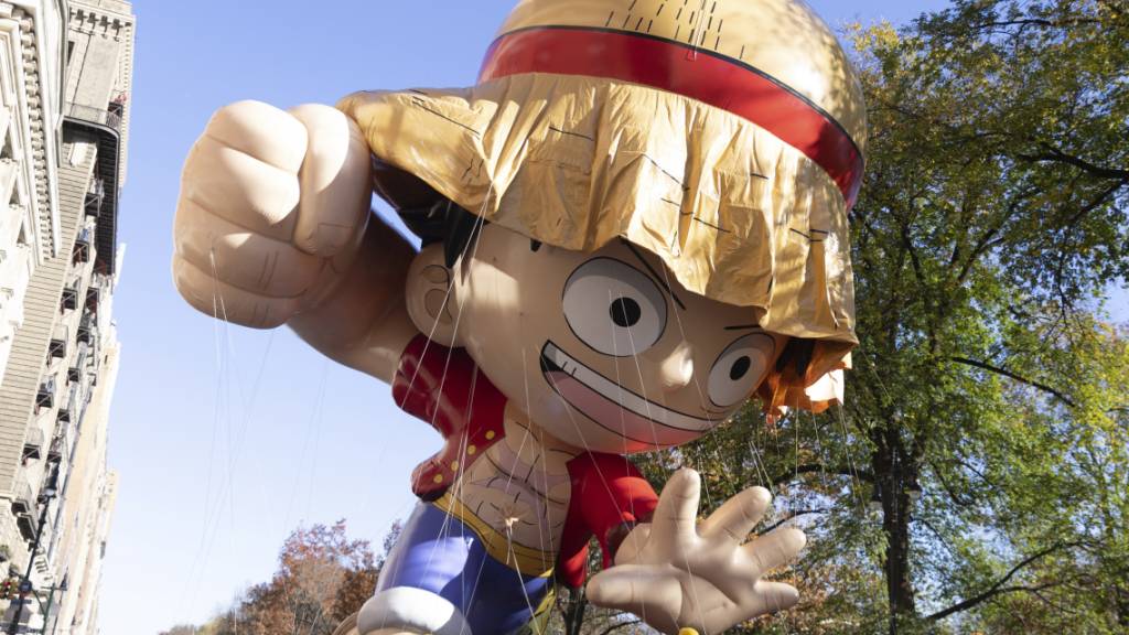 Helfer führen eine Ballon, der aussieht wie «Monkey D. Ruffy» aus der Animeserie One Piece, im Rahmen der traditionellen Thanksgiving-Parade an den Zuschauern auf den Balkonen des Central Park West vorbei. Foto: Jeenah Moon/AP/dpa