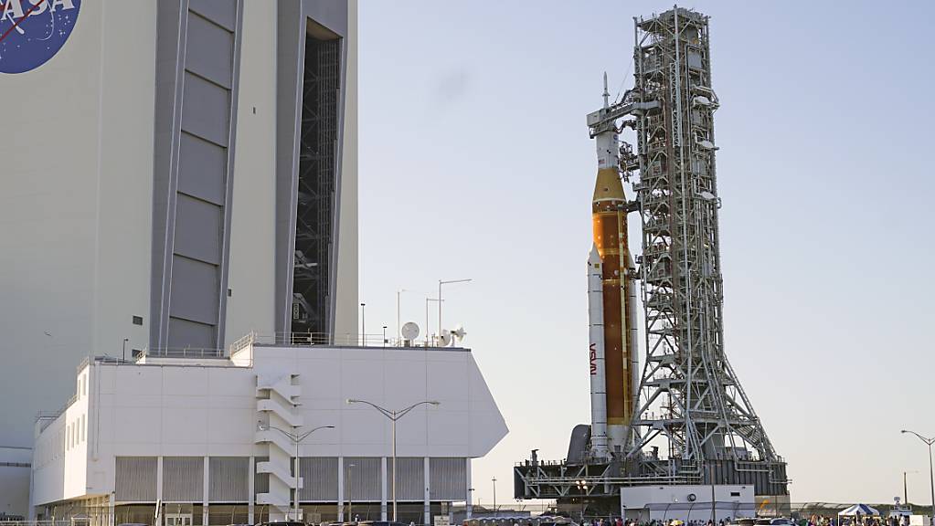Die Rakete «Space Launch System» mit der «Orion»-Kapsel wird auf einer Art Transportwagen aus der Werkshalle herausgefahren auf dem Weg zur Startrampe 39B im Kennedy Space Center.
