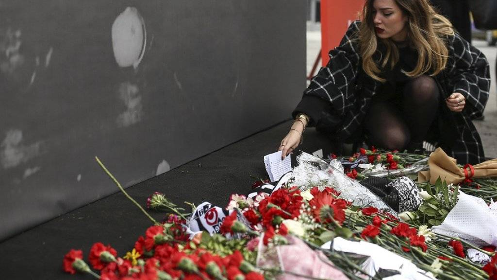 In Gedenken an die Opfer des Doppelanschlags von Istanbul legt eine Frau vor der Vodafone Arena, wo der türkische Fussballverein Besiktas seine Heimspiele austrägt, eine Nachricht nieder.