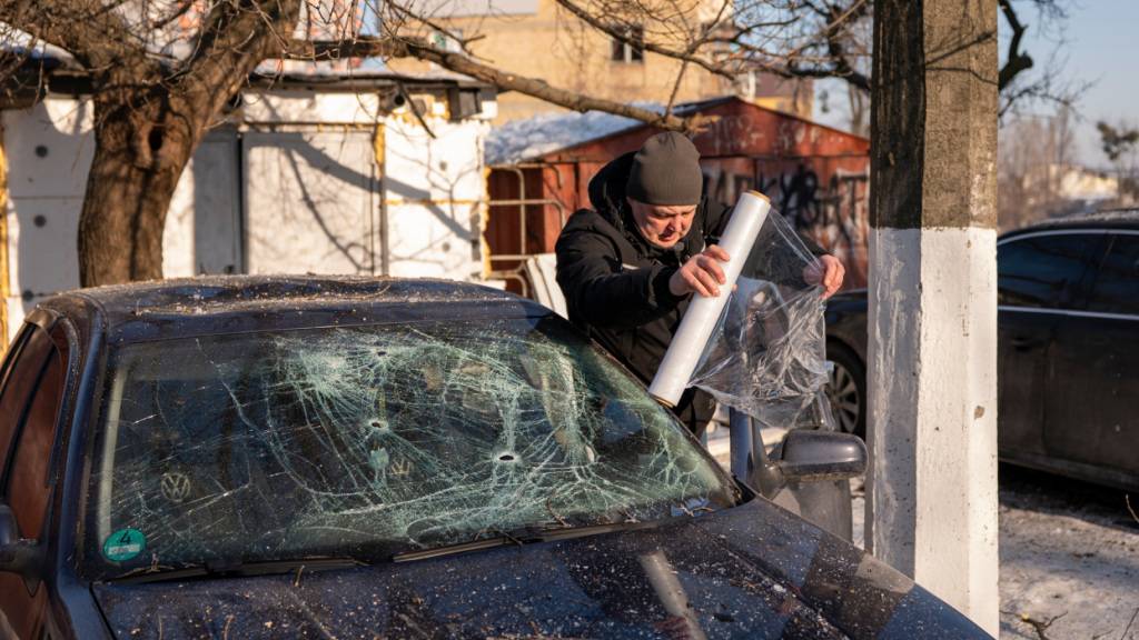 ARCHIV - Ein Autobesitzer wickelt sein Auto in Plastik ein, nachdem es nach einem russischen Raketen- und Drohnenangriff in Kiew, Ukraine, beschädigt wurde. Foto: Dan Bashakov/AP/dpa