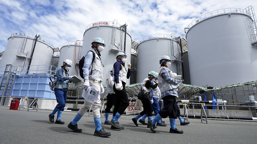 Journalisten werden an Tanks vorbei geführt, die behandeltes radioaktives Abwasser enthalten. Diese Tanks sind Teil der Anlage zur Ableitung von behandeltem radioaktivem Wasser aus dem Kernkraftwerk Fukushima Daiichi. Foto: Eugene Hoshiko/Pool AP/AP/dpa