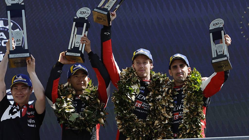 Sébastien Buemi (ganz rechts) und seine Teamkollegen Brendon Hartley (Mitte) und Ryo Hirakawa (Zweiter von links) winken in Le Mans vom Podest