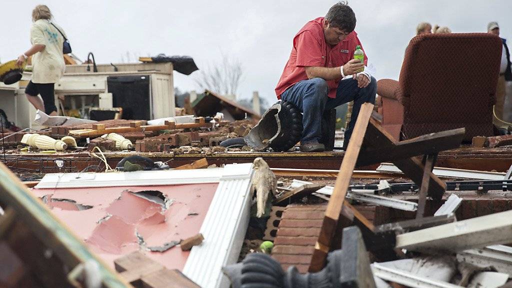 Ein Mann sitzt in den Trümmern seines durch einen Tornado zerstörten Hauses.